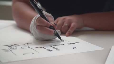 Person writing on paper with a bandage on their hand
