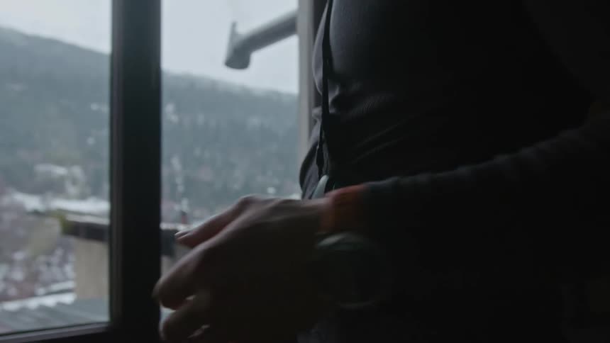 A man attaches a tech device to his belt and then picks up gloves and puts them in a duffel bag