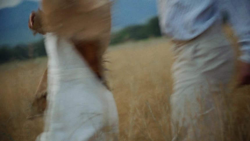 The couple is running handinhand through a brown field enjoying the fresh air and the beautiful scenery