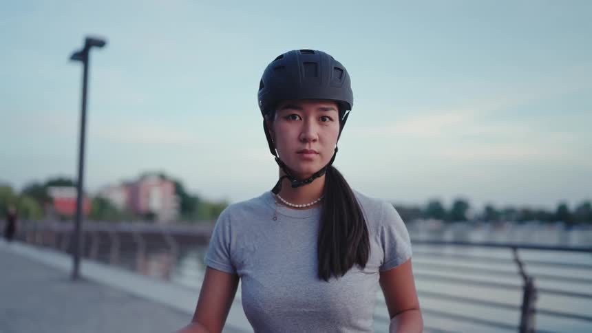 A woman is wearing a bicycle helmet by the shore