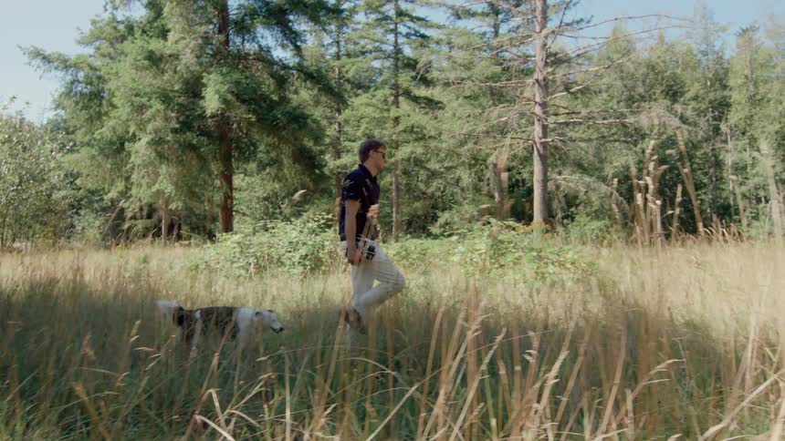 A man is hiking with his dog on a sunny day