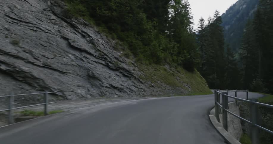 Moving view down a narrow street surrounded by mountains and conifers