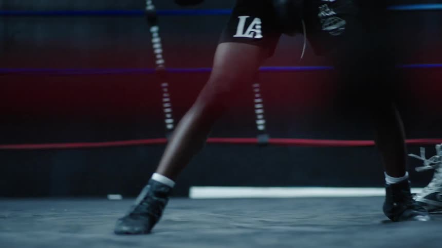 Two boxers feet wearing hightop boxing boots standing in a boxing ring