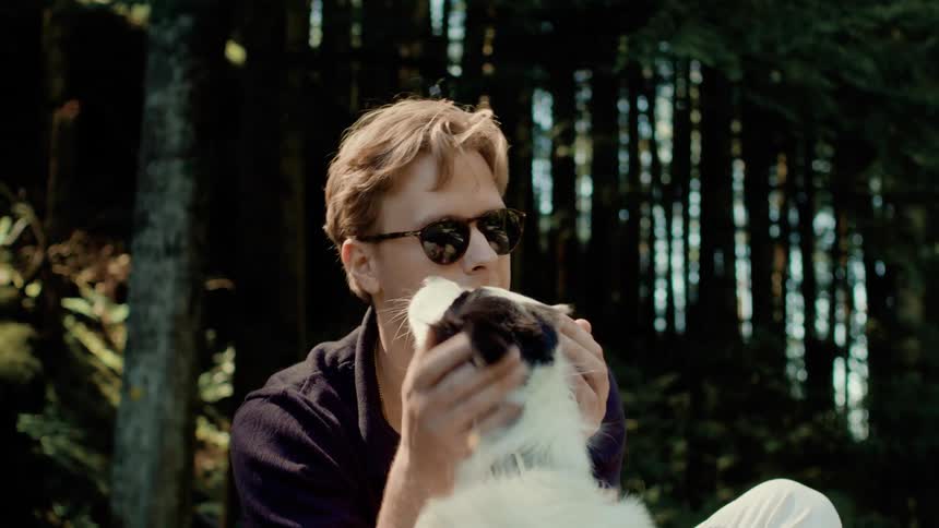 Man playing with his dog with trees in the background