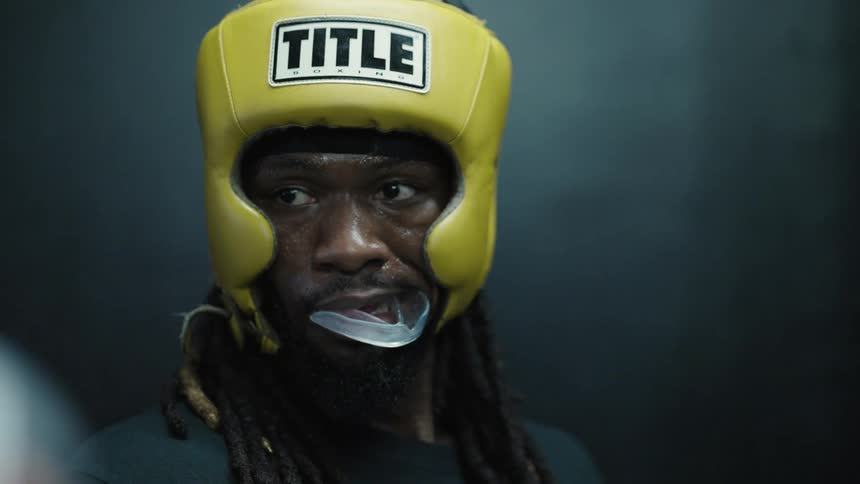 Male boxer wearing boxing gloves tries to put on his mouth guard