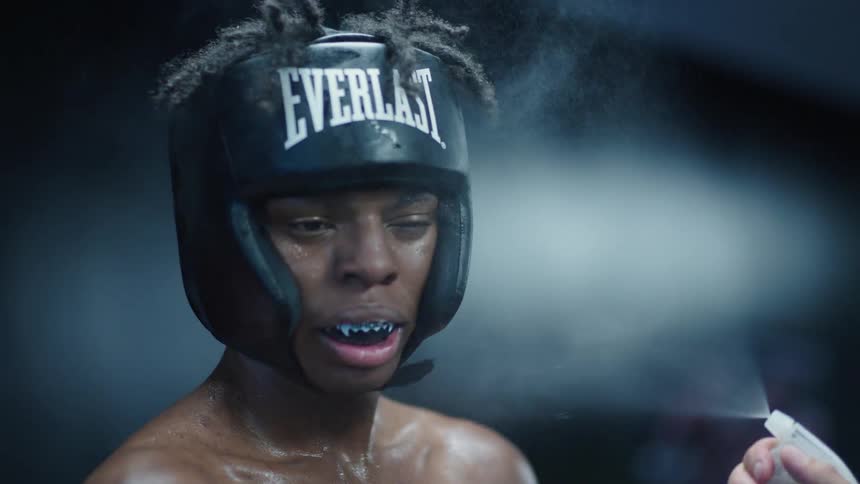 Trainer spritzes and wipes a boxer wearing boxing gear
