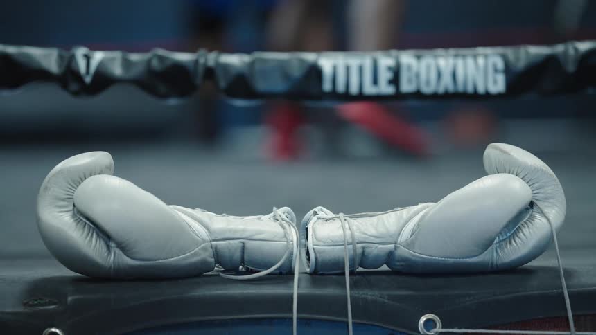 A pair of white boxing gloves lying on the canvas of a boxing ring