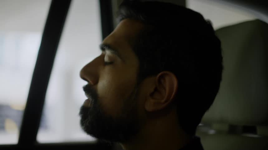 Side portrait of a bearded man inside a moving car as he looks out the window