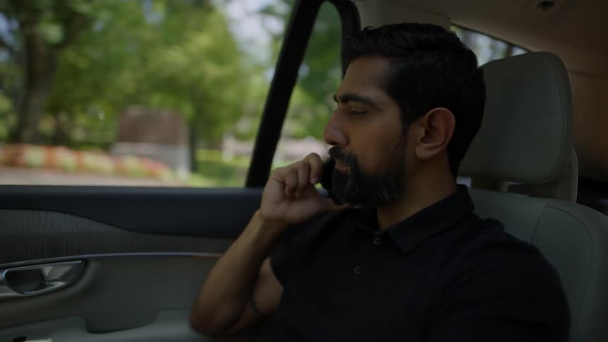 A man speaking on a smartphone and hanging up while in a moving car