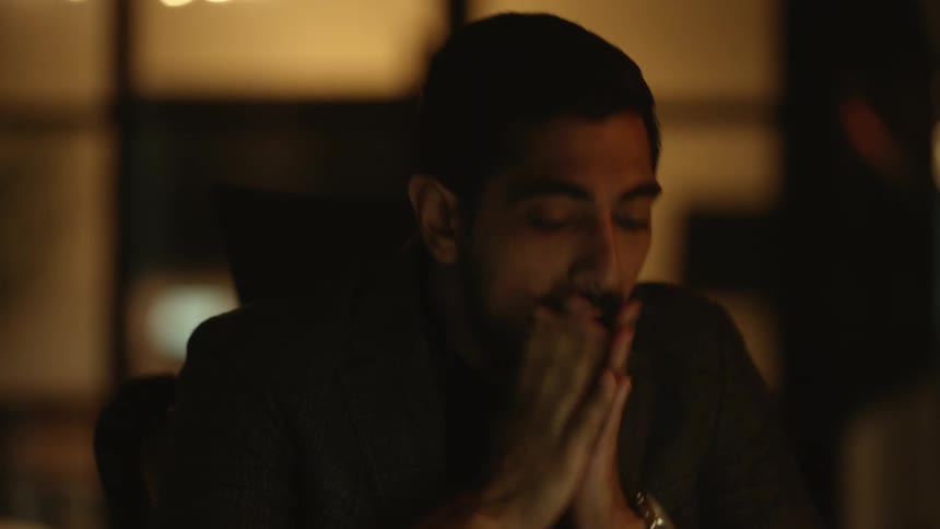 Man sitting in dimly lit room at night wipes his face
