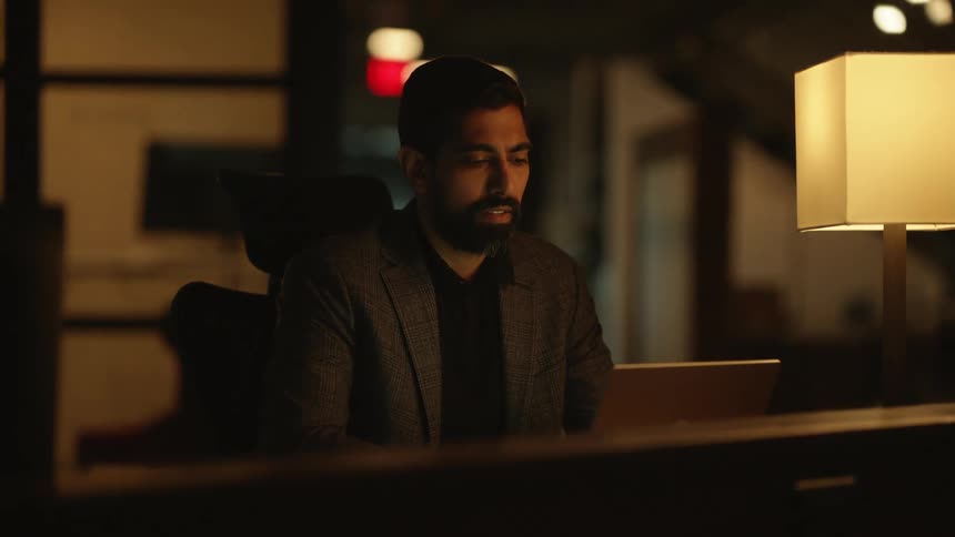 A young man works late at night in an office
