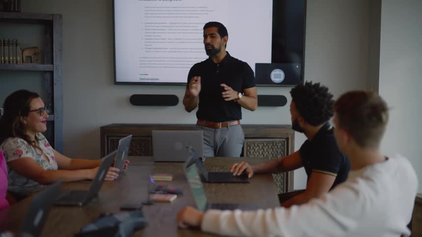 Man talks with his coworkers during a presentation in their office conference room