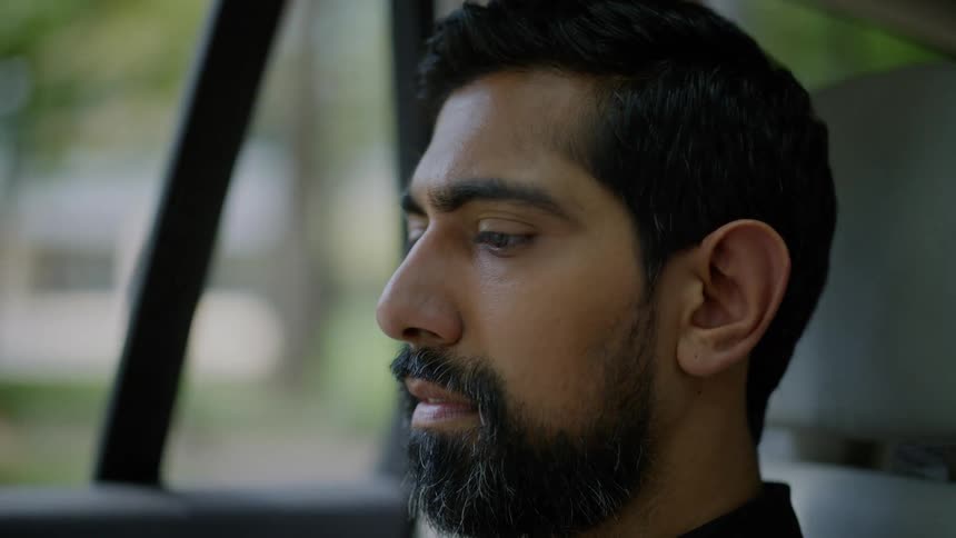 A man reads something while sitting in the passenger seat of a moving vehicle