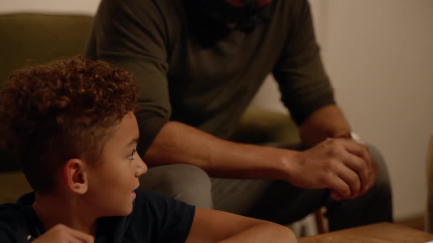 Child working on his homework in the living room talks to his parents
