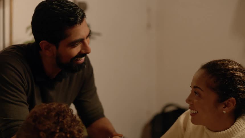 Mother and father smile while talking to each other in their living room with their child