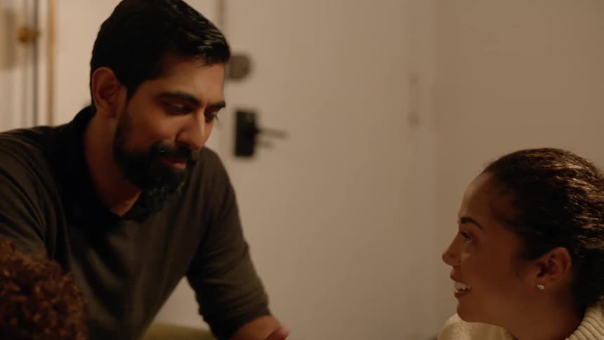 A man and woman sit together in a living room while chatting