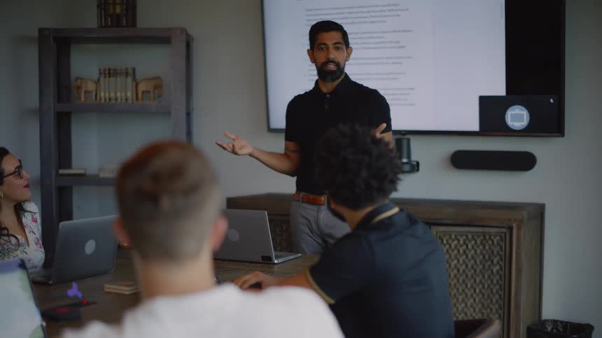 A man speaks to employees in an office conference room setting