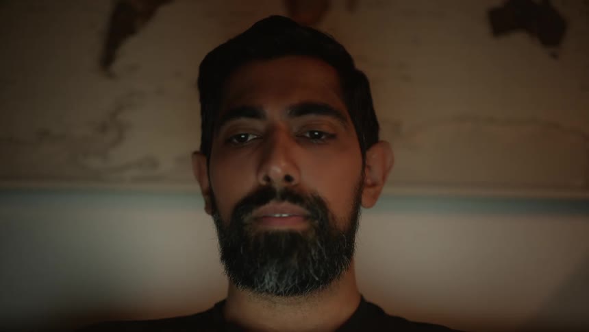 Bearded man looks down on laptop at night