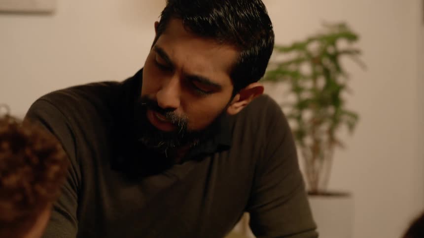 A man reclined over a table talking to his family at home