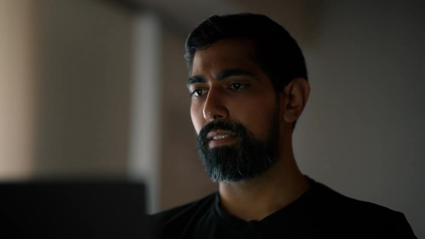 Bearded man wearing a black shirt uses a laptop