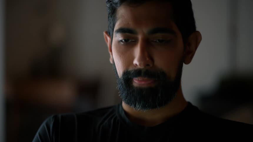 A bearded man is typing on his laptop in the morning