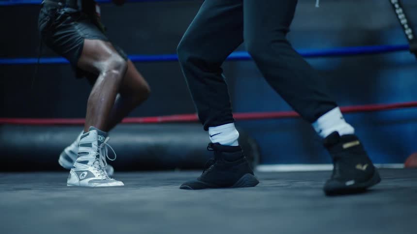Close up of the legs of two men sparring in a boxing ring