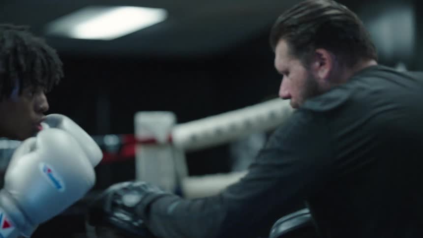 Two fighters spar in a ring at a boxing gym