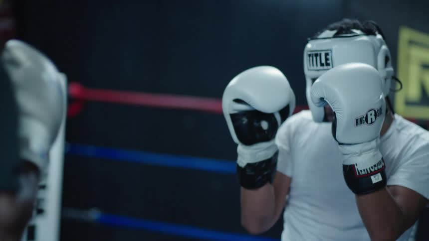 Two men sparring in a boxing ring wearing gloves and headgear