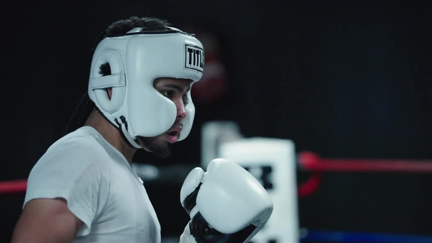 Two men sparring in a boxing ring wearing gloves and headgear