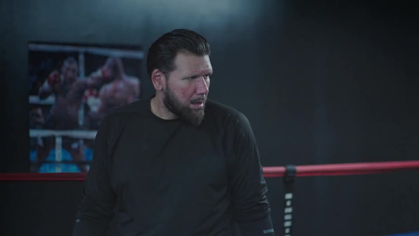 Trainer watching two young men fighting in a boxing ring