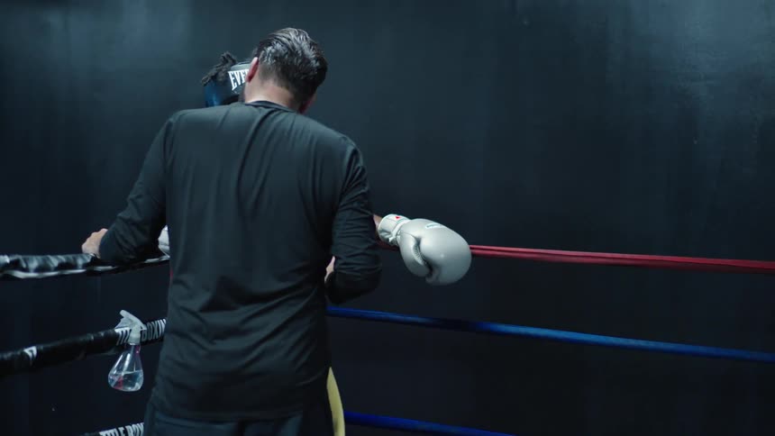 Trainer gives tired boxer water and spritzes him