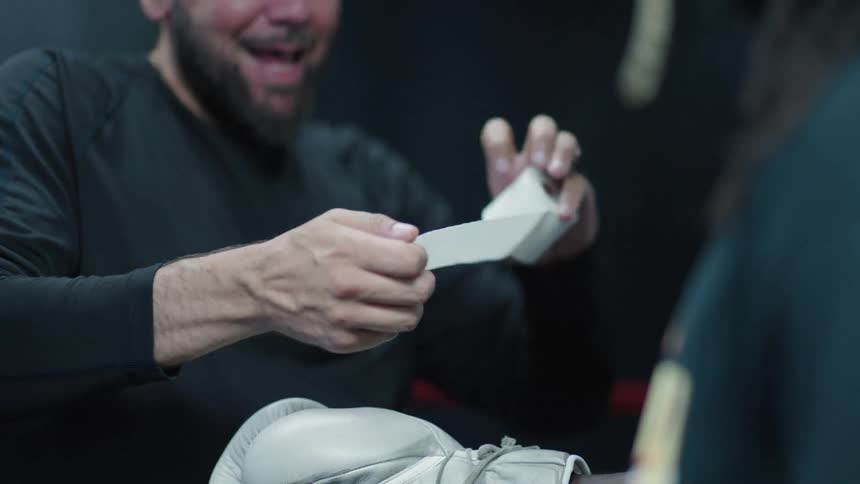 A white guy helps tie and tape a black boxers glove