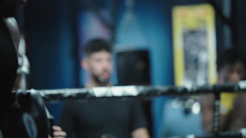 Two men boxing and a person outside watching