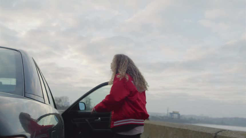 Young blonde woman getting out of the car in an angry manner and slamming the door