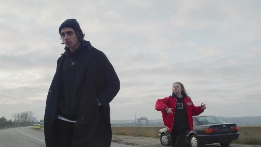 A man walks away from a yelling woman by crossing a road