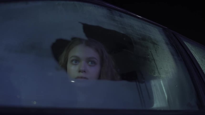 Woman with a scared expression looking out the window from inside the car