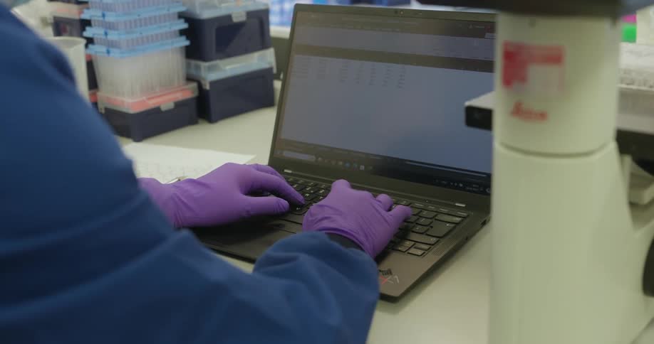 Hand with gloves typing on a laptop on the table