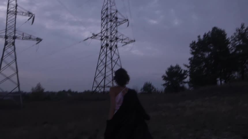 Back view of a woman running with a dog wearing a dress and a long coat