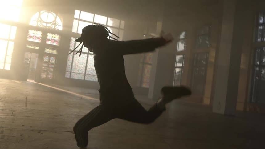 A person performs a dance move inside of a large empty building