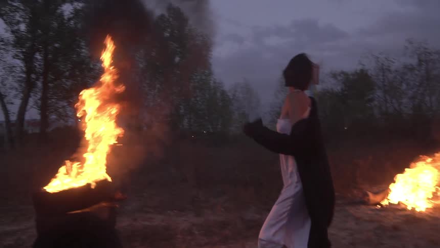 A woman runs through the flames and spins around