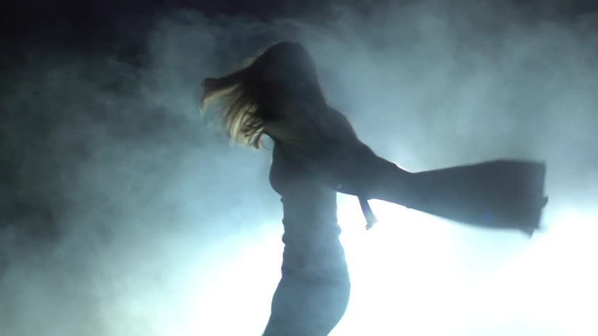 A woman is dancing in the fog