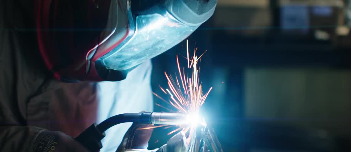 A person performing welding work with bright sparks flying from the welding point