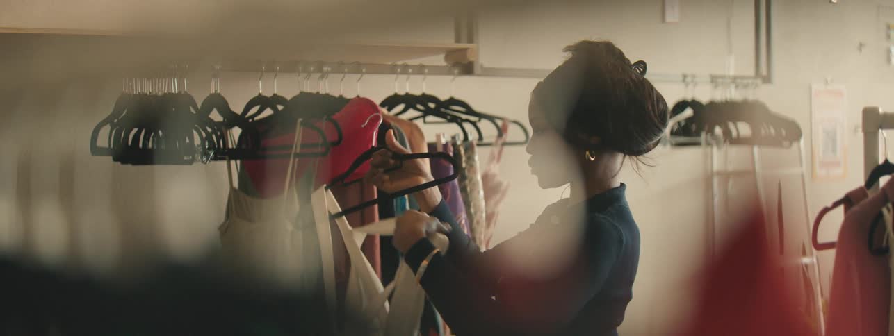 Woman putting clothes onto a hanger in a clothing store while organizing stock.