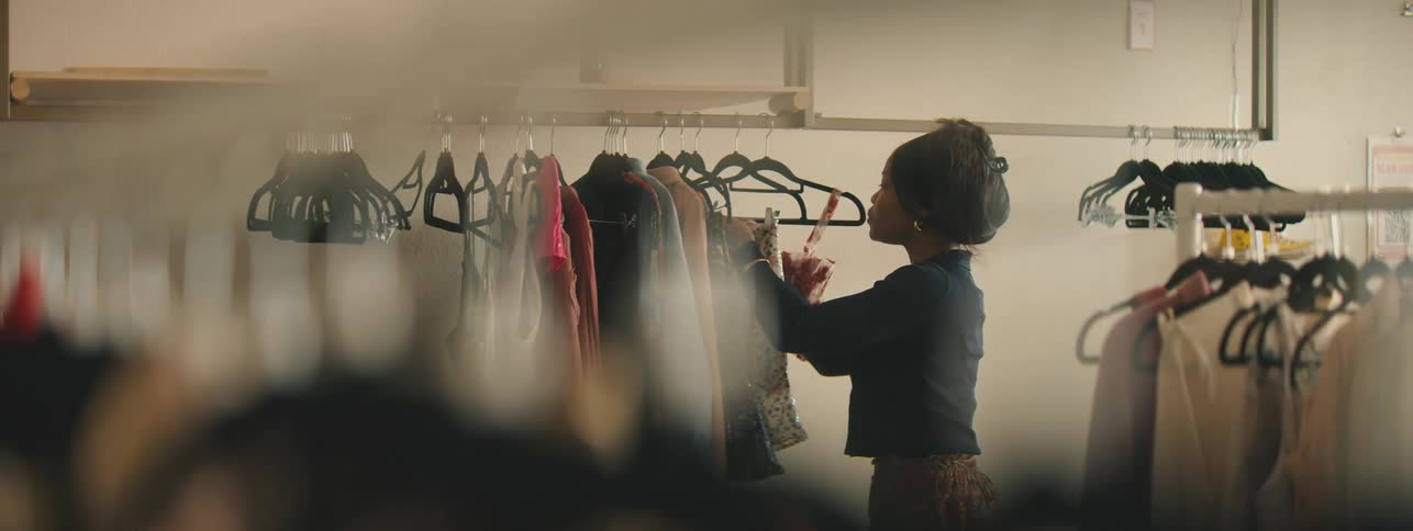 Woman placing labels on clothes in a store during garment setup for display.