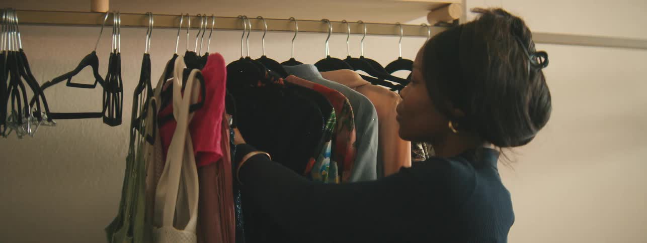 In a boutique fashion store, a woman checking labels on garments hanging on a rack.