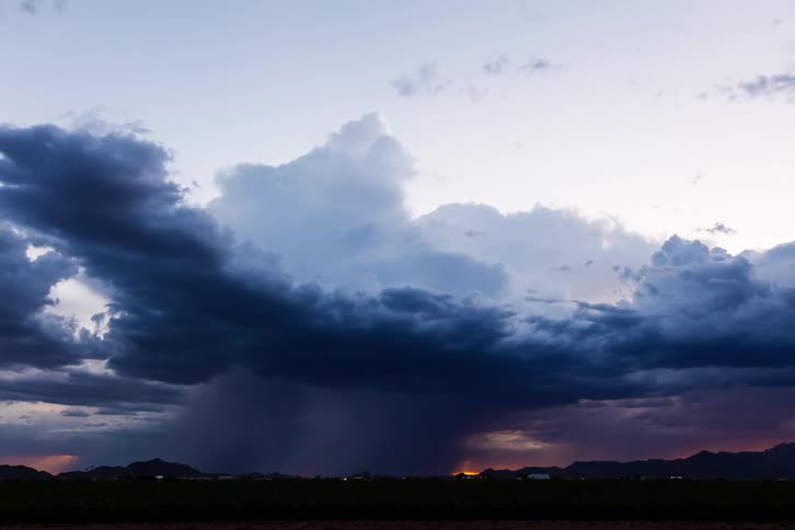 Silhouette of mountains and storm darkening the sky with thunder and rain