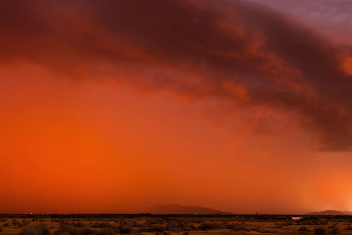Lightning storm moving across the land leaving an orange haze behind