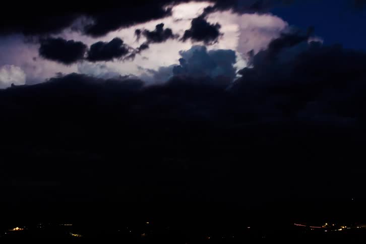 Darkening sky and multiple lightning bolts light up the sky in a thunderstorm