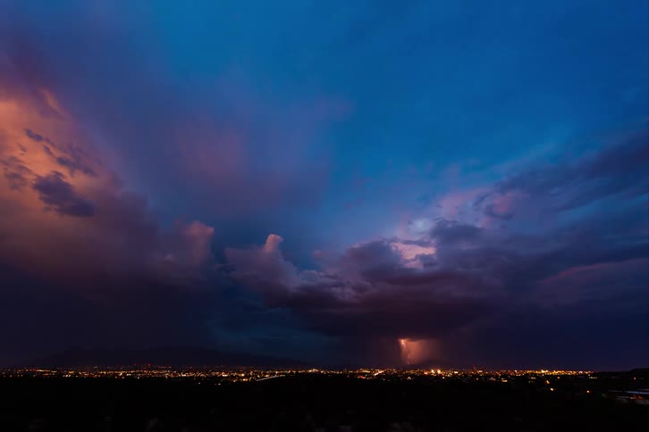 Landscape with the city skyline lit up and the sky darkened by a thunderstorm