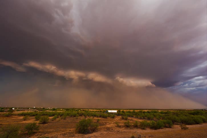 Lightning storm causes a dust cloud over traffic and a semi truck in a field